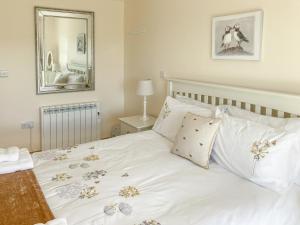 a bedroom with a white bed with flowers on it at Ardstinchar Mews in Ballantrae +16 photos