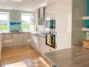 a kitchen with white cabinets and a clock on the wall at Ardstinchar Mews in Ballantrae