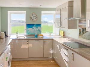 a kitchen with a sink and a clock on the wall at Ardstinchar Mews in Ballantrae