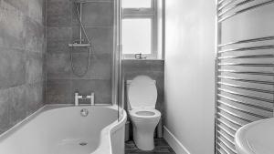 a bathroom with a toilet and a tub and a sink at Parkview Apartment in Rothesay