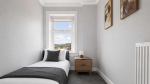 a small bedroom with a bed and a window at Parkview Apartment in Rothesay