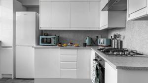 a white kitchen with a stove and a microwave at Parkview Apartment in Rothesay