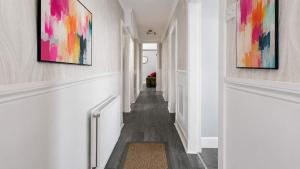 a hallway with white walls and paintings on the walls at Parkview Apartment in Rothesay +3 photos