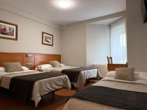 a room with three beds and a window at Hostal Restaurante Iruñako in Burgos +83 photos