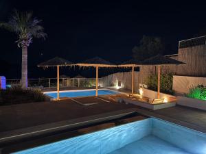 a swimming pool at night with umbrellas at Lindian Jewel Hotel and Villas in Lindos