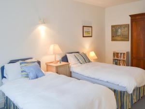 two twin beds in a room with a lamp at Topsail in Newton Ferrers