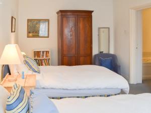a bedroom with two beds and a wooden cabinet at Topsail in Newton Ferrers