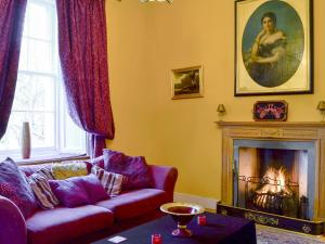 a living room with a couch and a fireplace at Lochside Garden House - S4484 in Town Yetholm