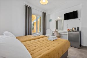 a bedroom with two beds and a flat screen tv at Kamelia Hotel in Spetses