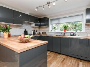 a kitchen with black cabinets and a bowl of fruit on a counter at Sheeoch in Comrie