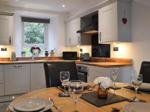 a kitchen with a wooden table with wine glasses on it at Coniston Cottage in Coniston