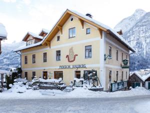 a large building with snow on the ground at Pension Hallberg in Hallstatt