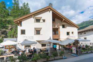 a building with tables and umbrellas in front of it at Chesa Survial 4 in Sils Maria