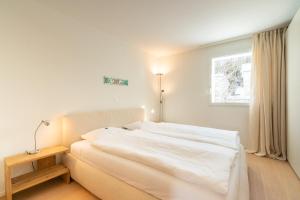 a white bed in a room with a window at Residenza Edelweiss 5 3 in Sils Maria