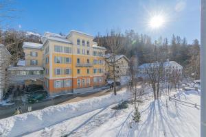 a large yellow building on a city street in the snow at Residenza Edelweiss 5 3 in Sils Maria