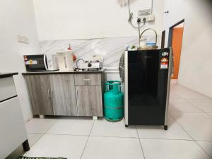 a kitchen with a refrigerator and a trash can at De'Bendang Homestay Pendang in Pendang