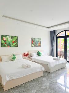 two beds in a room with white walls at Tropical Bay Villas and Homestay in Phú Quốc