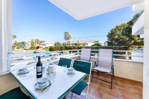 a table with a bottle of wine and chairs on a balcony at Apartamento Veleta Puerto Pollensa in Pollença