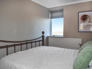 a bedroom with a white bed and a window at Marina Views in Amble
