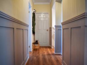 an empty hallway with a door and a cat sitting on a chair at Marina Views in Amble +8 photos