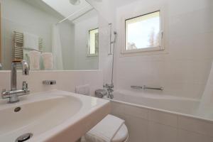 a white bathroom with a sink and a mirror at Residenza Alpenrose 22 in Sils Maria +7 photos