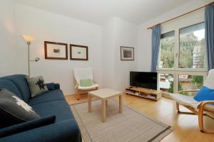 a living room with a blue couch and a tv at Residenza Alpenrose 22 in Sils Maria