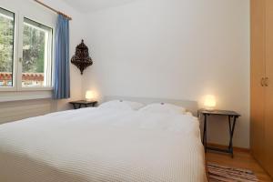 a white bed in a room with a window at Residenza Alpenrose 22 in Sils Maria