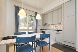 a kitchen with a white table and blue chairs at Residenza Alpenrose 22 in Sils Maria