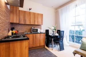 a kitchen with wooden cabinets and a table with a microwave at Elicia's South Kensington Apartment in London