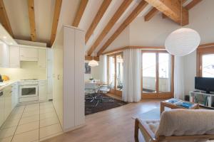 a kitchen and living room with white cabinets and a table at Chesa Cravunera 29 in Sils Maria