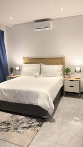 a bedroom with a large bed with white sheets and pillows at The Captains Suite in Gaborone