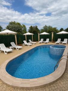 a swimming pool with lounge chairs and umbrellas at Hotel Margarita in Kranevo