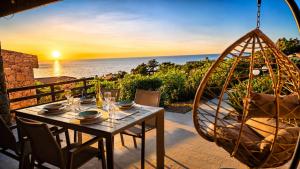 a table with chairs and a swing with the sunset at Villetta Vista Paradiso in Costa Paradiso
