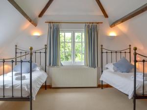 two beds in a bedroom with a window at The Stables in Eardisland