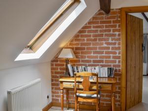 an attic room with a desk and a brick wall at The Stables in Eardisland +4 photos