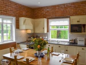a kitchen with a wooden table and a brick wall at The Stables in Eardisland