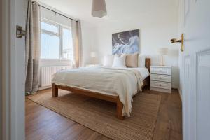 a white bedroom with a large bed and a window at Hot Tub With A View - Christchurch Harbour in Christchurch