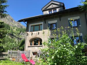 a house with two red chairs in front of it at Chesa Clos in Sils Baselgia