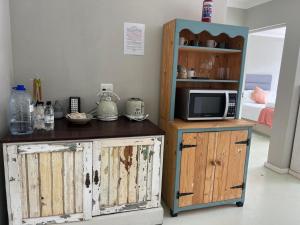 a room with a tv and a cabinet with a microwave at Fever Tree B&B in Gonubie Manor