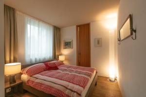 a bedroom with a bed with red pillows and a window at Chesa Piol in Maloja