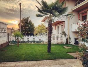 a palm tree in a yard next to a white fence at Irpinia Maison in Quarto dʼAltino