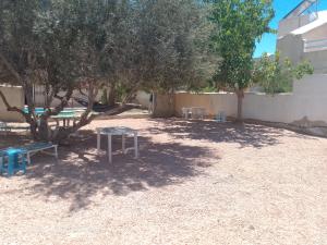 a picnic table and two chairs under a tree at villa Flori Midoun in Djerba