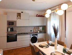 a kitchen with white cabinets and a table with chairs at Irpinia Maison in Quarto dʼAltino +7 photos