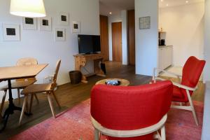 a living room with a table and red chairs at Chesa Piol Studio in Maloja +10 photos