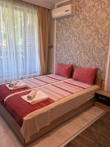 a bedroom with a large bed with red sheets at Green apartments in Primorsko