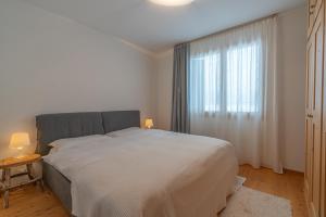 a white bedroom with a large bed and a window at Chesa Blaunca B4 in Maloja