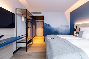 a bedroom with a large bed and a blue wall at Holiday Inn - the niu, Quay Hamburg Harburg by IHG in Hamburg +151 photos