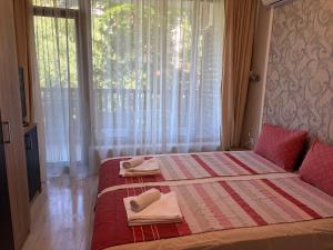 a bedroom with a bed with towels and a window at Green apartments in Primorsko