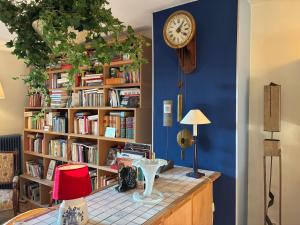 a book shelf filled with books with a clock on it at La Vigne - Han-sur-Lesse in Han-sur-Lesse