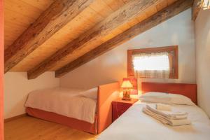 two beds in a room with wooden ceilings at Chesa Cavril in Maloja
